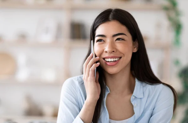 Comunicación moderna. Alegre chica asiática hablando por teléfono celular en casa, disfrutando de la conversación — Foto de Stock