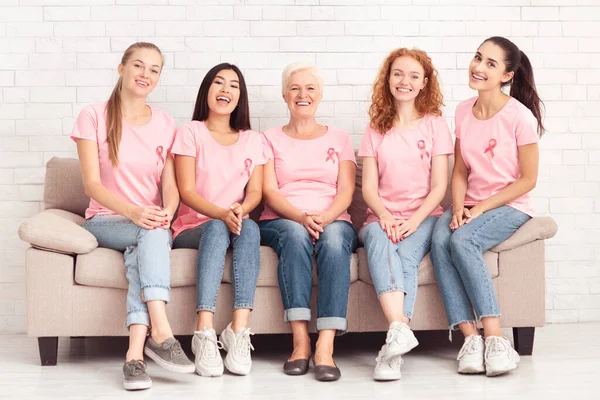 분홍색 티셔츠를 입고 실내에 앉아 있는 쾌활 한 다 문화 여성들 — 스톡 사진