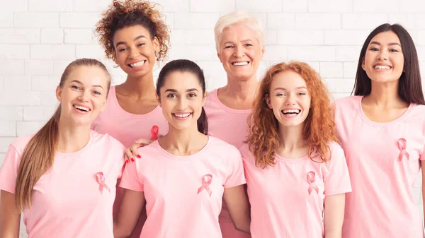 Señoras sonriendo usando camisetas con cinta rosa sobre fondo blanco — Foto de Stock