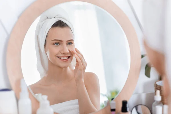 Feliz joven mujer usando crema facial después de la ducha —  Fotos de Stock