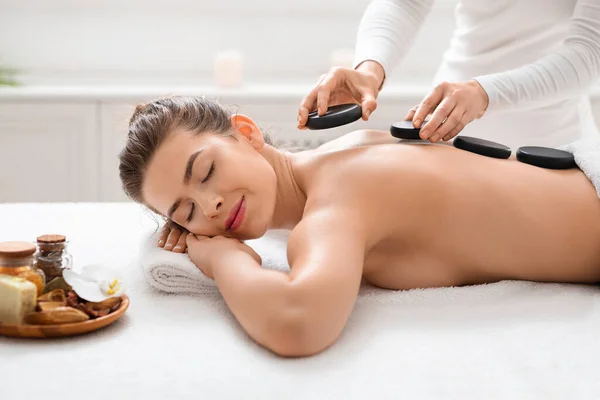 Mulher desfrutando de seu dia no spa, recebendo massagem pedras quentes — Fotografia de Stock