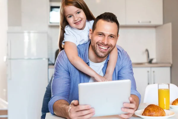 Pai e filha usando tablet tomando café da manhã juntos em casa — Fotografia de Stock