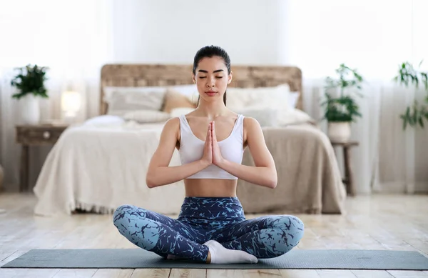 Inhemsk yoga. Ung sportig asiatisk flicka mediterar i Lotus position — Stockfoto