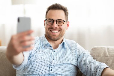 Video görüşmesi veya selfie için akıllı telefon kullanan mutlu bir adam.