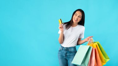 Alışveriş torbaları ve plastik kartlarla gülümseyen kadın.