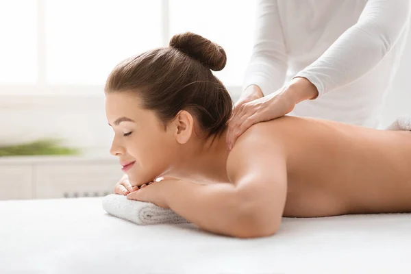Massagista esfregando jovem mulher ombros no spa — Fotografia de Stock