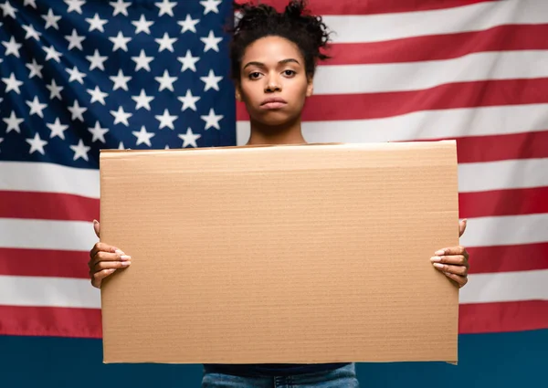 Черная девушка, стоящая с пустым картоном над американским флагом — стоковое фото