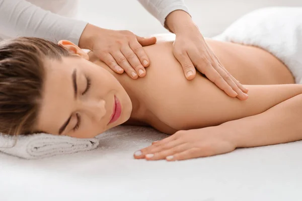 Sluiten van massage therapeut handen wrijven slapende vrouw lichaam — Stockfoto