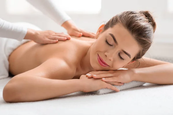 Gioiosa giovane donna che frequenta il salone termale, ottenendo massaggio alla schiena — Foto Stock
