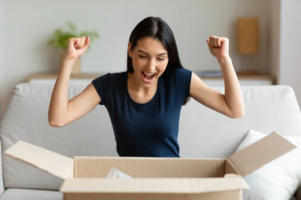 Opgewonden meisje uitpakken pakket doos zitten op bank thuis — Stockfoto