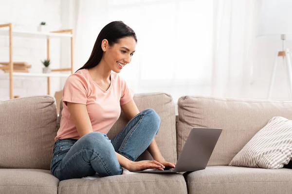 Frau mit Laptop auf Sofa sitzend — Stockfoto