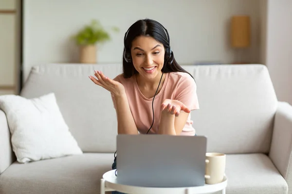 Vrouw in de headset met behulp van laptop computer maken van videogesprek binnen — Stockfoto