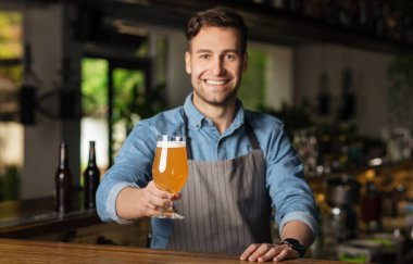 El yapımı bira. Gülümseyen barmen kameraya bakar ve bir bardak içki verir.