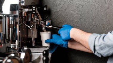 Kafe ve karantina. Lastik eldivenli barista kahve makineli kapuçino yapar.