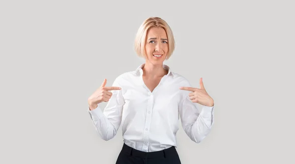 Vergrijzing. Volwassen zakenvrouw die twijfelachtig naar zichzelf wijst, ongelukkig met nominatie of ontslag op lichte achtergrond — Stockfoto