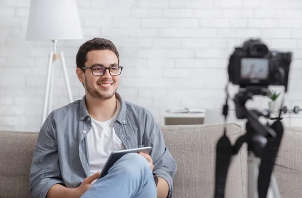 Famoso blogger. Sonriente joven con la tableta en las manos graba vídeo en la cámara —  Fotos de Stock