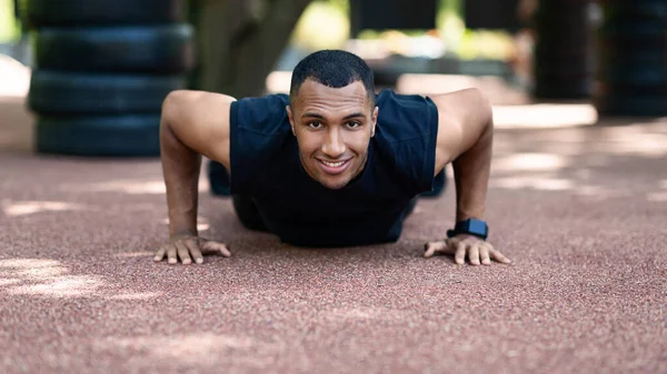 Zwarte duizendjarige sportman doet push-ups op jogging track in het park — Stockfoto