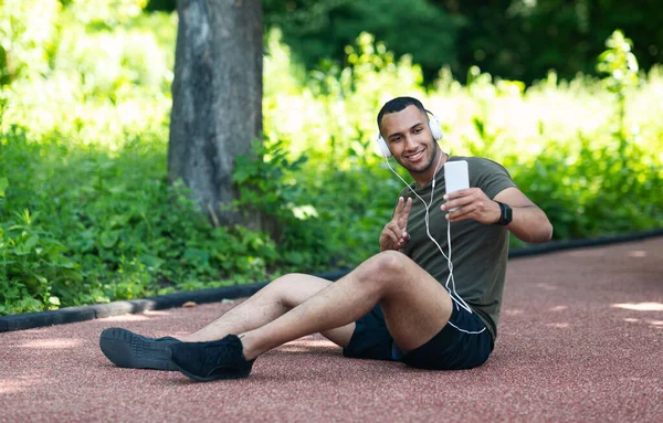 Afroamerikanischer Läufer macht Selfie während er sich nach seinem Training im Park ausruht — Stockfoto