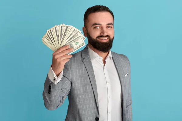 Feliz empresario sosteniendo ventilador de dinero americano sobre fondo azul —  Fotos de Stock