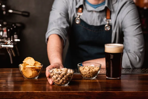 Menú del pub. Barman en delantal da bocadillos en platos y cerveza oscura con espuma en la barra — Foto de Stock