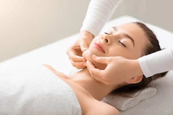 Rilassato giovane signora avendo lifting massaggio al viso a spa — Foto Stock