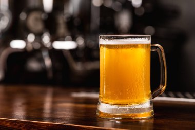 Fıçıdan en sevdiği taze bira. Ahşap tezgahta bulanık arka planda bir bardak light bira.