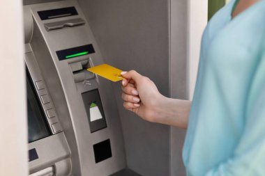 Tanınmayan bir kadın nakit almak için ATM 'ye altın kredi kartı koyuyor.