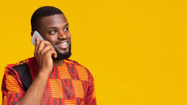 İlgilenen Afrikalı bir adam telefonda konuşuyor, boş alana bakıyor.