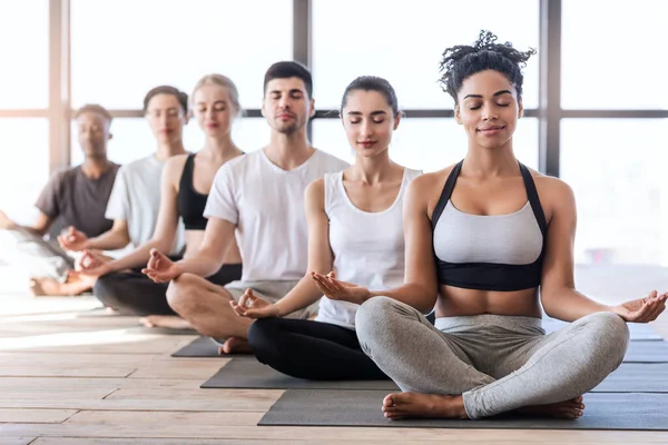 Lezione di yoga. Gruppo di giovani sportivi che meditano con gli occhi chiusi — Foto Stock