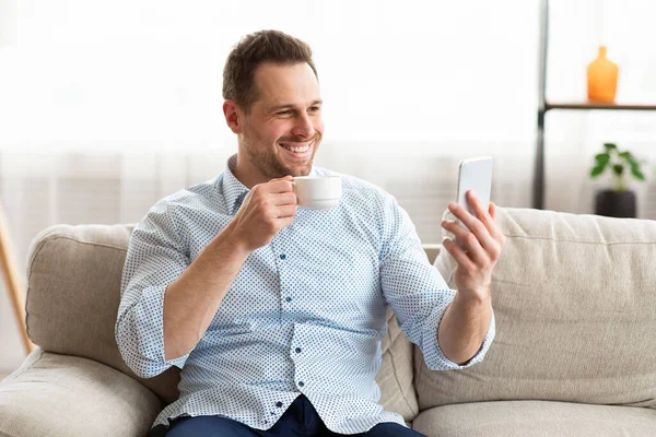 幸せな男を使用してスマートフォンで自宅 — ストック写真