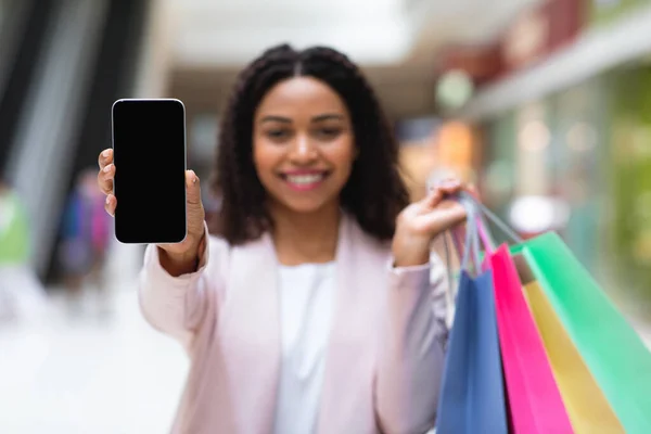 Korting App. Glimlachende vrouw toont smartphone met zwart scherm in het winkelcentrum — Stockfoto