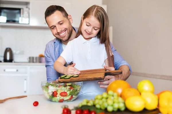 キッチンで野菜サラダを作るパパと子供の女の子の料理 — ストック写真