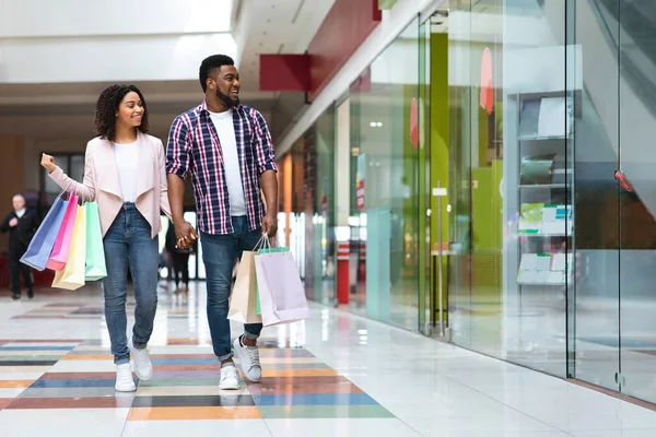 Vendas sazonais. feliz casal preto andando no centro comercial depois de comprar roupas — Fotografia de Stock