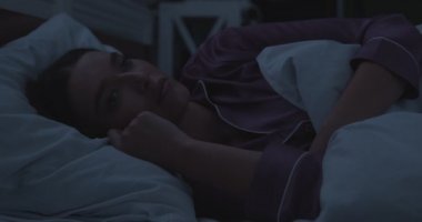 Geceleri yatakta uykusuzluk çeken bir kadın.