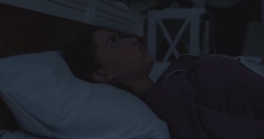 Gecenin geç saatlerinde yatakta yastıkla kulaklarını kapatan sinirli genç bir kadın.