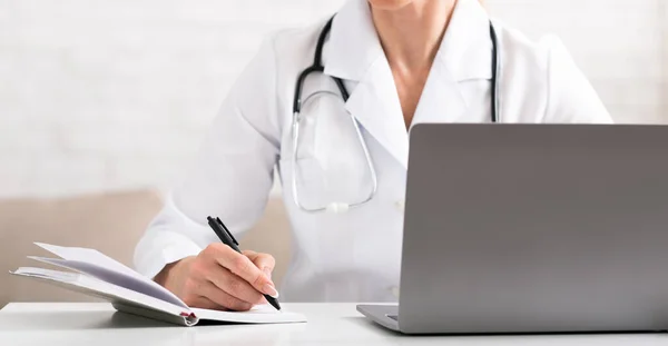 Paciente enfermo se queja al médico a la llamada de conferencia, utilizando el ordenador portátil. Mujer de abrigo blanco hace notas en cuaderno —  Fotos de Stock