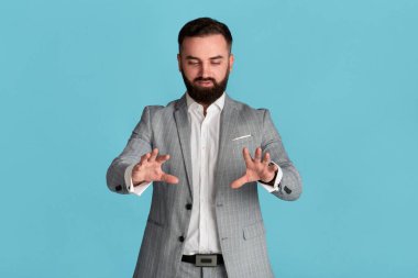 Ciddi genç girişimci mavi arkaplan üzerinde etkileşimli sanal ekrana dokunuyor, tasarım için alan