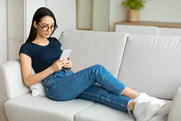 Estudiante chica usando teléfono móvil chateando en línea sentado en casa — Foto de Stock