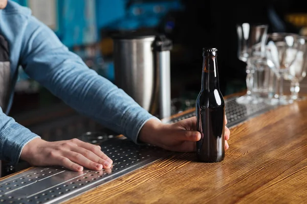 パブでリラックス。バーテンダーはバーカウンターの顧客にラベルなしのビールのボトルを提供します。 — ストック写真