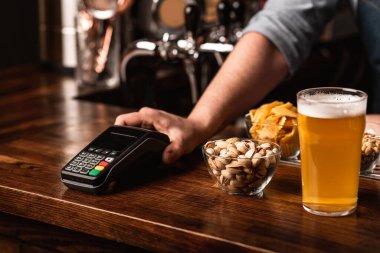 Pub 'da faturalar ve ödeme. Barmen, barın içinde aperatifli bira seti ve terminal veriyor.