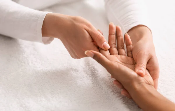 Ritagliato di massaggiatrice facendo massaggio alle mani per la signora africana — Foto Stock