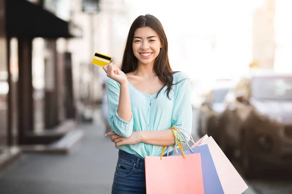 Asiatisk flicka Posing utomhus med färgglada väskor och kreditkort efter shopping — Stockfoto