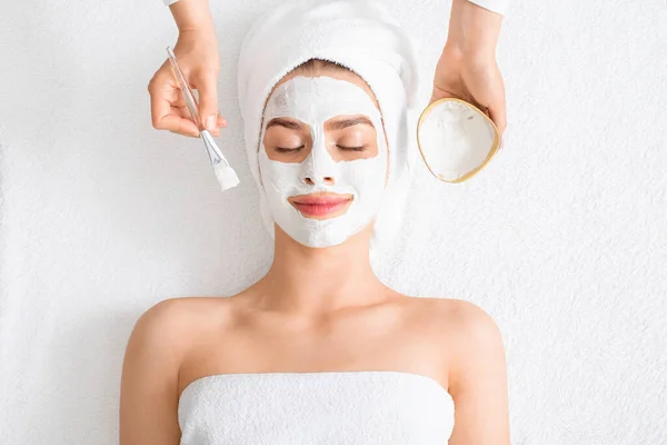 Terapeuta de spa colocando máscara facial para jovem senhora — Fotografia de Stock