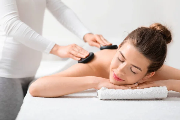 Junge Dame erhält Massage mit heißen Steinen im modernen Wellnessbereich — Stockfoto