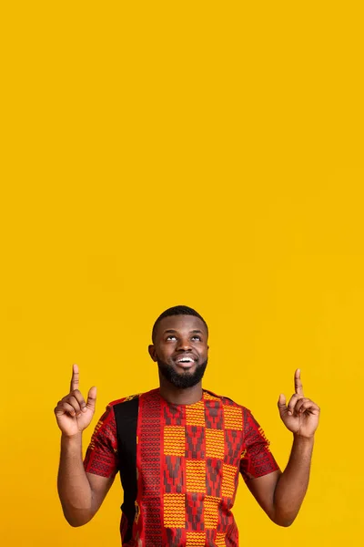 Snygg afrikansk man i traditionella kläder pekar uppåt — Stockfoto