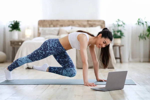 Entrenamiento en casa. Joven asiática chica practicando deporte en frente de portátil — Foto de Stock