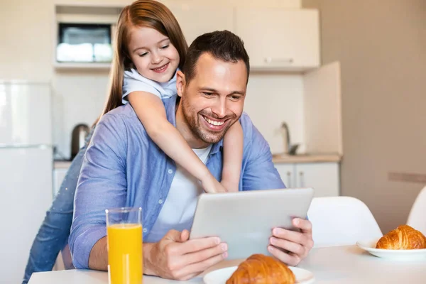 Pai alegre e filha usando Tablet durante o café da manhã na cozinha — Fotografia de Stock