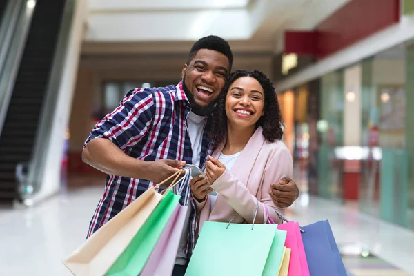 Ventes saisonnières. Conjoints africains posant dans le centre commercial avec beaucoup de sacs à provisions — Photo