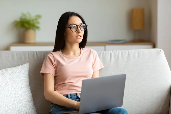 Student Dziewczyna siedzi z laptopem myślenia siedzi na kanapie w domu — Zdjęcie stockowe