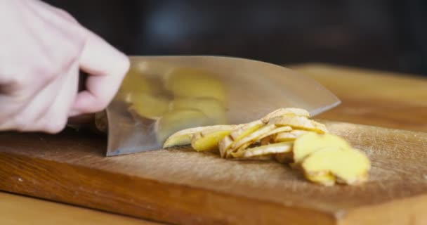 Femme coupant racine de gingembre frais sur la table de cuisine, gros plan — Video